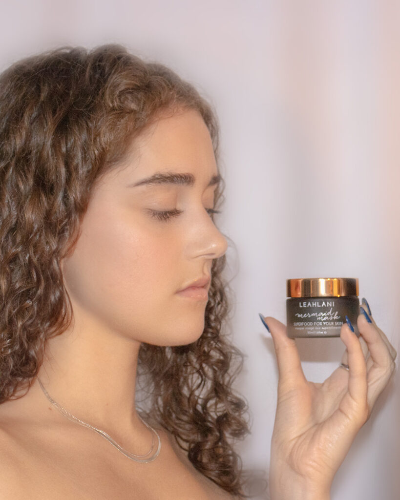 girl looking at a little container that she is holding on a white background